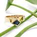 Yellow gold engagement ring with teal kite sapphire resting on green plant stems