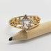 Front view of yellow gold ring with shield cut sapphire and vine filigree on a pencil