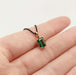 Emerald cut green tourmaline pendant in yellow gold on black chain shown on hand
