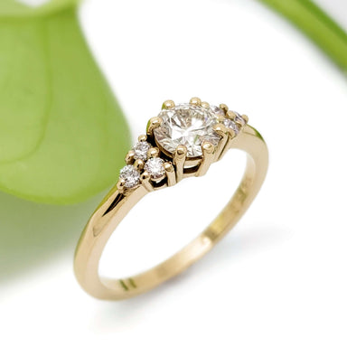 Handcrafted yellow gold engagement ring with lab-grown diamond and accent stones, leaf background