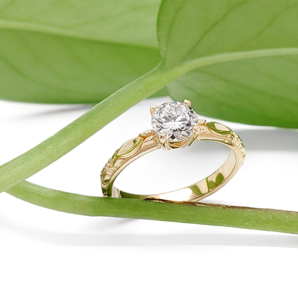 Yellow gold lab diamond engagement ring with leaf details, styled with green leaves