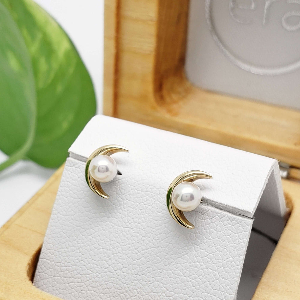 Pearl moon stud earrings in yellow gold displayed in a wooden jewellery box