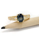 Yellow gold ring with blue-green sapphire and diamonds, displayed on a pencil
