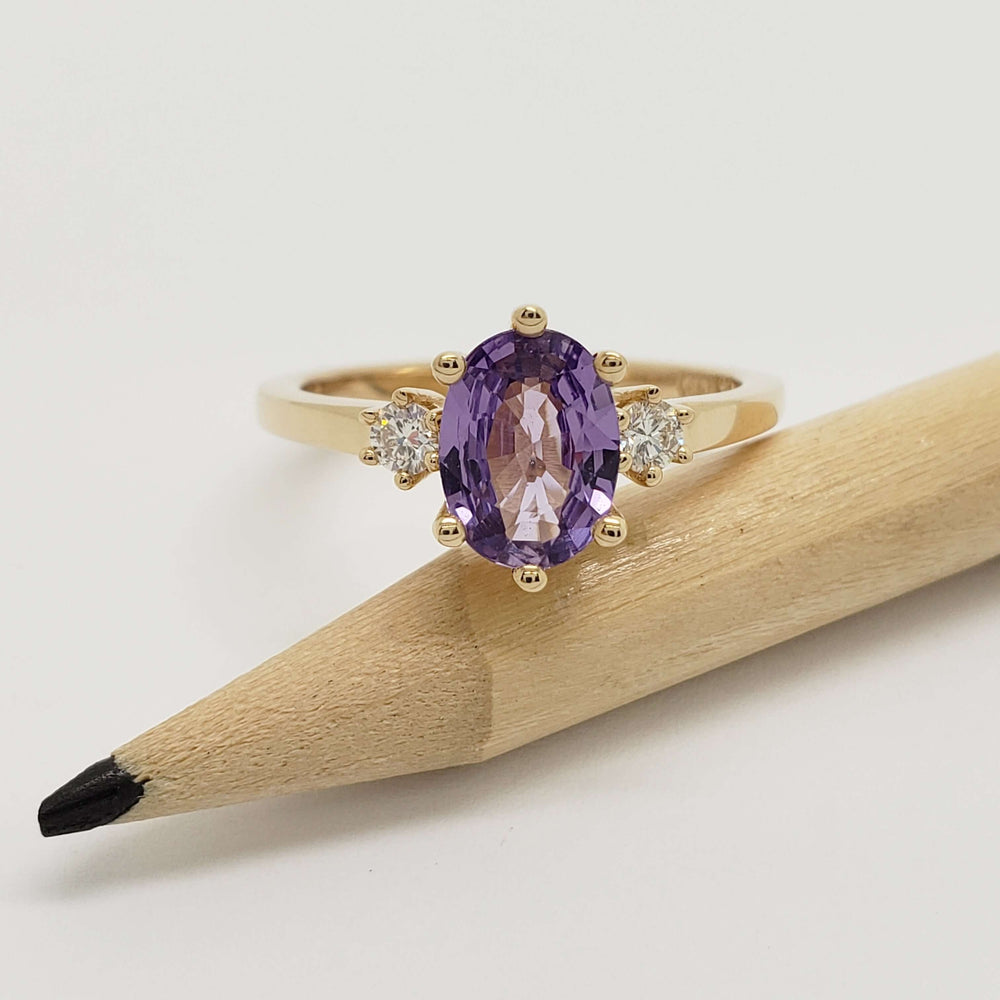 Front view of yellow gold ring with oval lavender sapphire and two lab grown diamonds