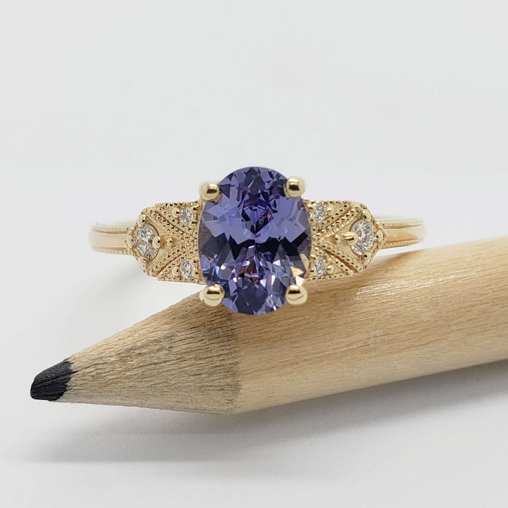 14kt yellow gold sapphire and diamond ring displayed on a pencil