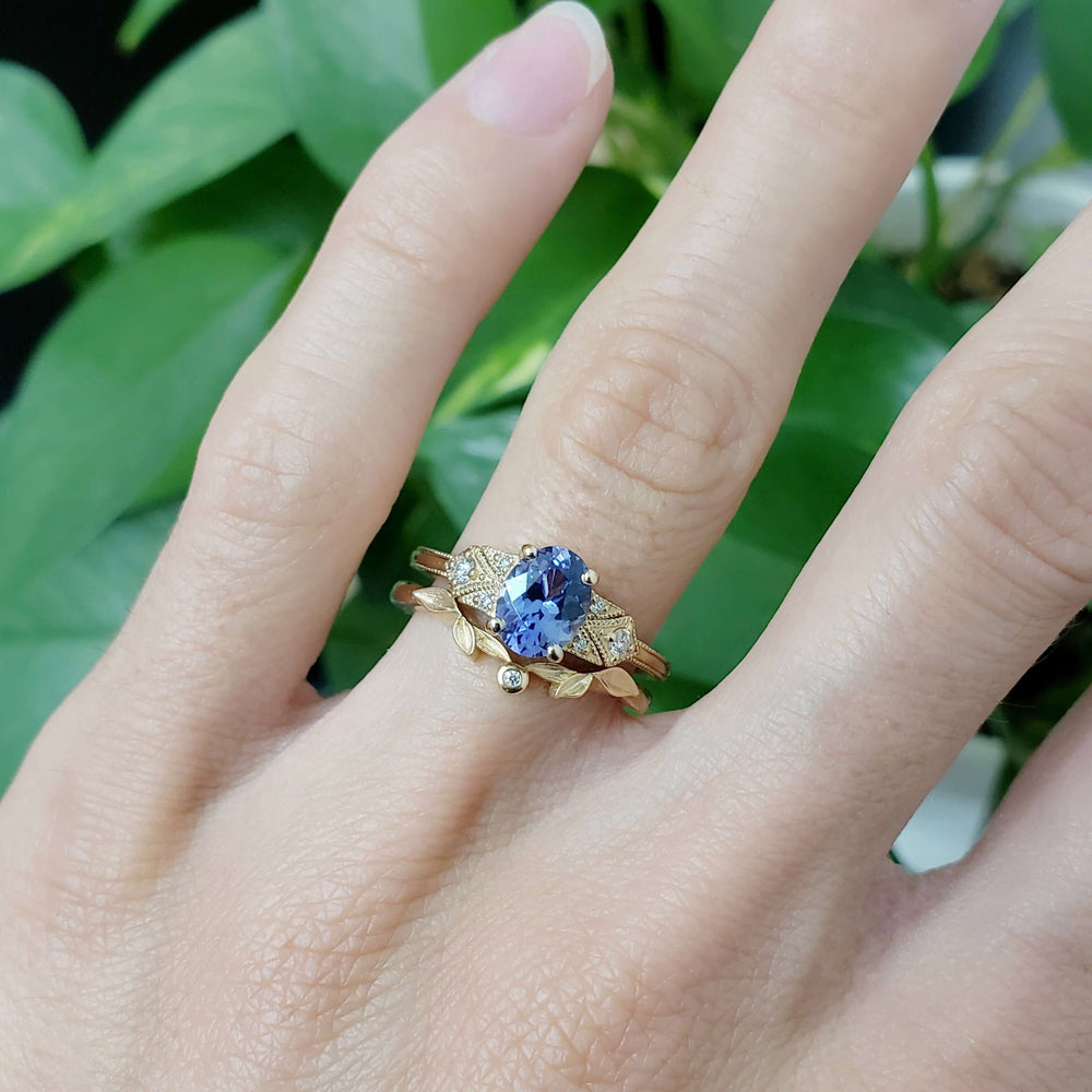 Yellow gold sapphire and diamond ring stacked with leaf-inspired band on hand