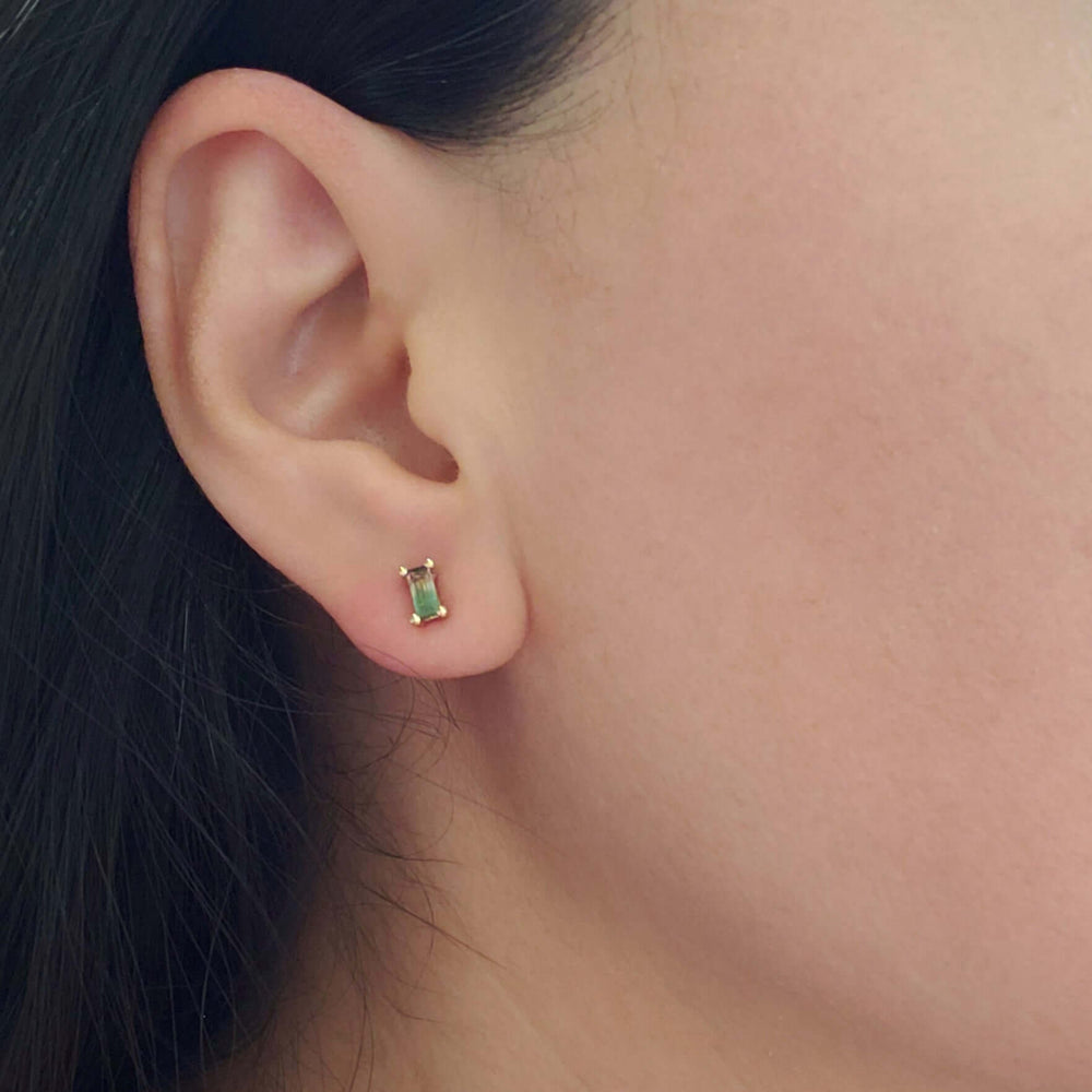 Watermelon tourmaline baguette stud earring in yellow gold worn on an ear