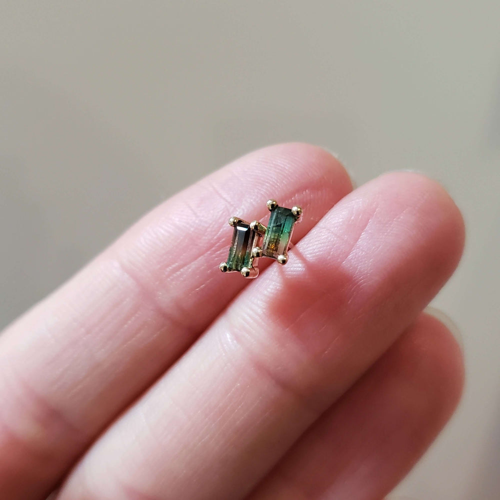 Baguette watermelon tourmaline stud earrings in yellow gold shown on a hand