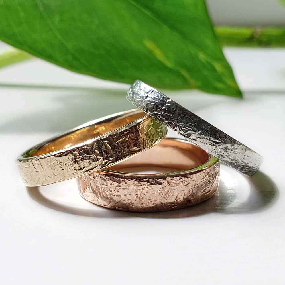 Three handcrafted wedding bands in yellow, rose, and white gold with elephant skin texture