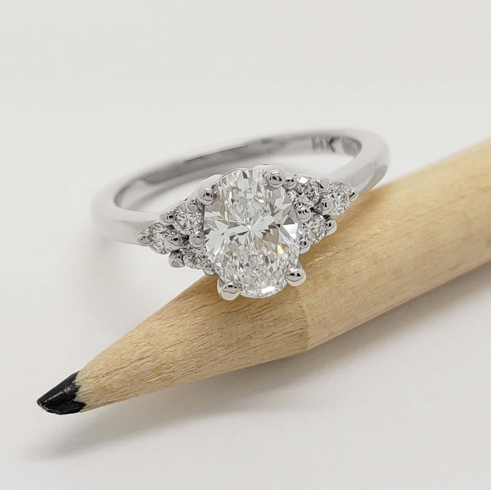 Zira engagement ring with oval lab diamond and side stones, shown next to a pencil
